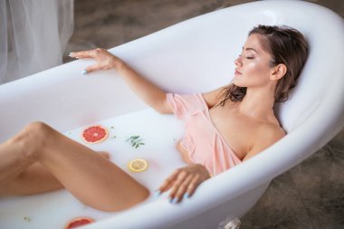 Genç bir esmer kadın süt banyosu yapıyor..