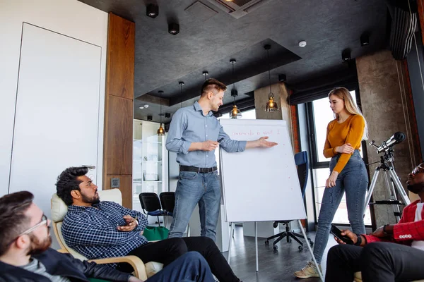 Gente multiétnica que planea estrategia de negocio con esquema en el rotafolio — Foto de Stock