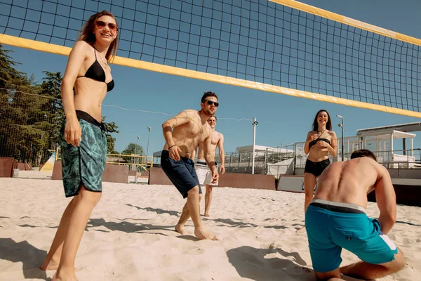 Grupo de jovens jogando vôlei de praia na areia — Fotografia de Stock