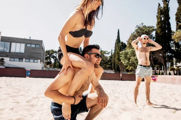 Bonito jovem dando passeio de piggyback para sua namorada na praia de verão — Fotografia de Stock