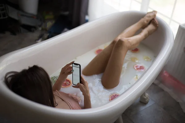 Hög vinkel syn på kvinnan med hjälp av smartphone medan du badar hemma — Stockfoto
