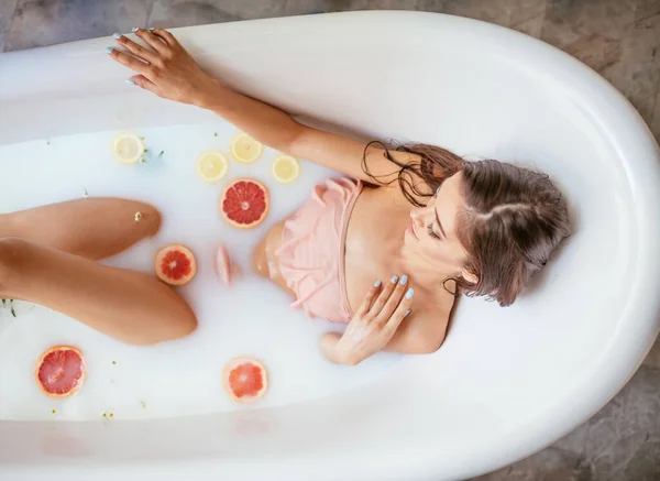 한 젊은 갈색 머리 여자가 우유 목욕을 한다. — 스톡 사진