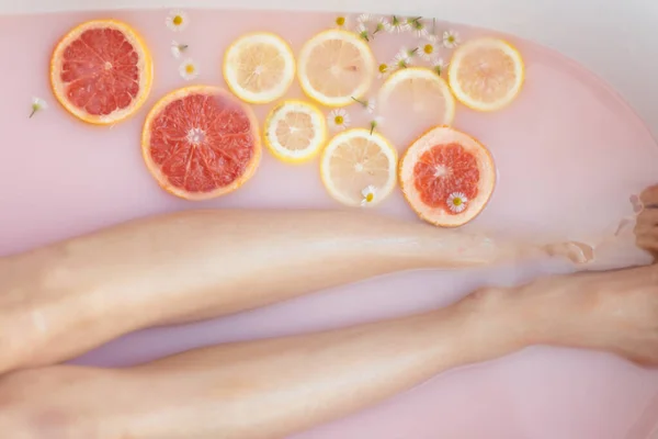 Kvinnor ben närbild i rosa mjölkaktig bad, Spa rekreationsterapi — Stockfoto