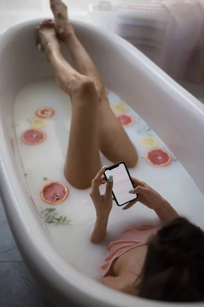 Портрет красивой азиатки с мобильного телефона, принимающей ванну дома — стоковое фото