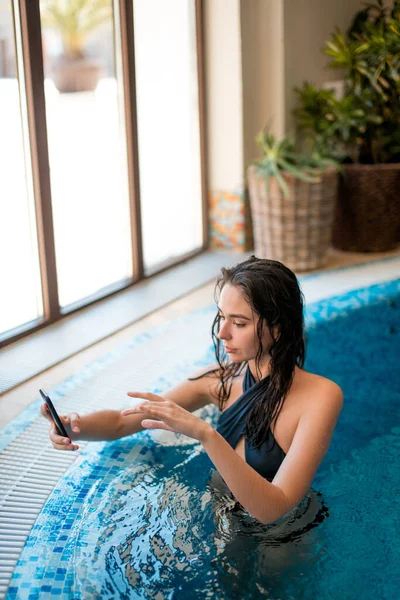 Jovem menina feliz tirar uma selfie na piscina interior no centro de bem-estar — Fotografia de Stock