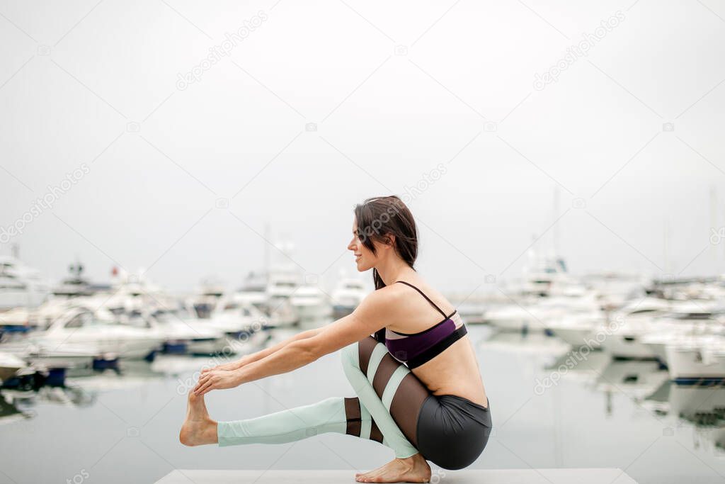 Woman doing yoga on marine pier - relaxing in nature.