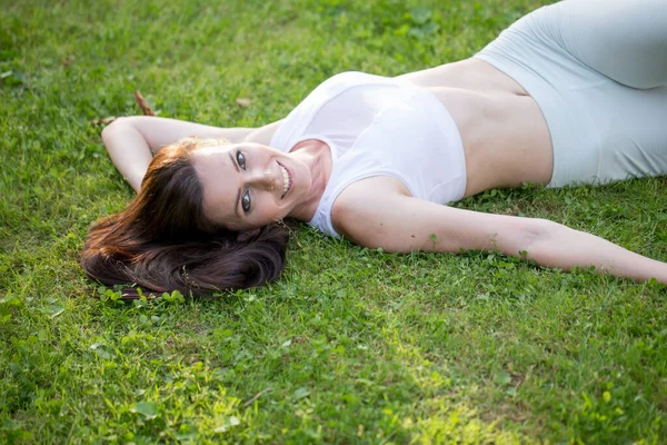 Joyeuse femme allongée sur l'herbe verte sur la medow du parc. En plein air. Profitez de la nature. — Photo
