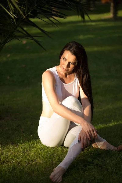 Chica de yoga sentada en la hierba, disfrutando del clima matutino en el parque —  Fotos de Stock