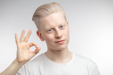 Pozitif sarışın adam, tamam işareti gösteriyor, her şeyin yolunda olduğunu gösteriyor.