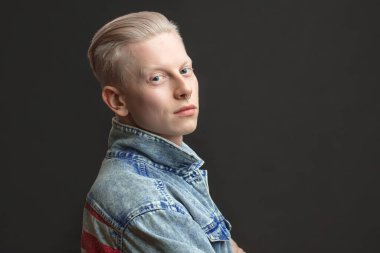 Kot jaket giyen yakışıklı sarışın Amerikalı adam siyah arka planda izole edilmiş.