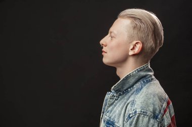 Kot jaket giyen yakışıklı sarışın Amerikalı adam siyah arka planda izole edilmiş.