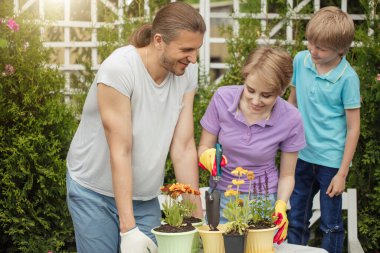 Young mother gardening in front or back yard with her two cute little children clipart