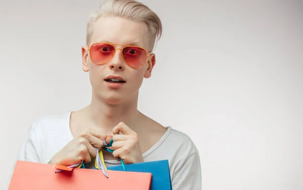 Moda portresi. Pembe gözlüklü, alışveriş çantalı genç adam. — Stok fotoğraf