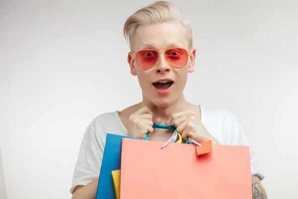 Retrato de hombre joven de moda en gafas de color rosa con bolsas de compras — Foto de Stock