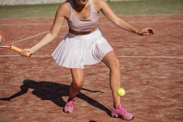 Portret van vrouwelijke benen met tennisracket op het veld. close-up afbeelding — Stockfoto