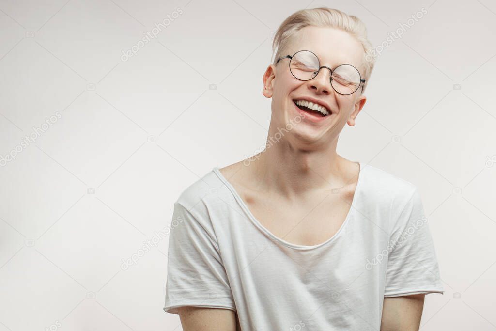 Hipster guy with blond hair smiling having cheerful look. Positive emotions