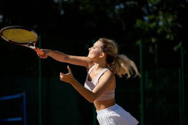 Sahada tenis oynamak için top servis eden bir kadın.