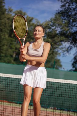 Tenis oyuncuları güneşli bir günde sahada maç yapıyorlar.