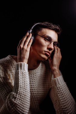 Beyaz süveter ve güneş gözlüğü takan yakışıklı bir erkek modelin stüdyo fotoğrafı.