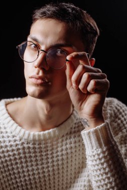 Beyaz tişört ve güneş gözlüğü takan yakışıklı bir erkek mankenin stüdyo fotoğrafı.