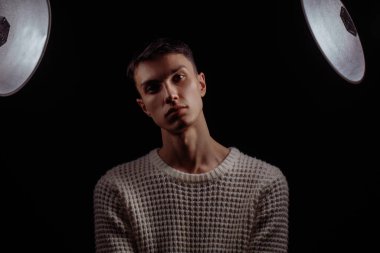 Beyaz tişört ve güneş gözlüğü takan yakışıklı bir erkek mankenin stüdyo fotoğrafı.