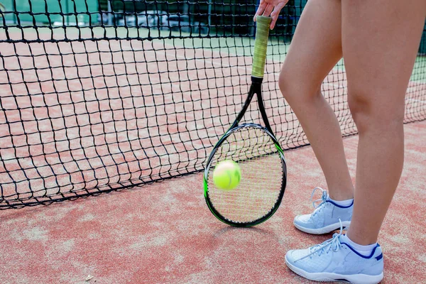 Portret van vrouwelijke benen met tennisracket op het veld. close-up afbeelding — Stockfoto