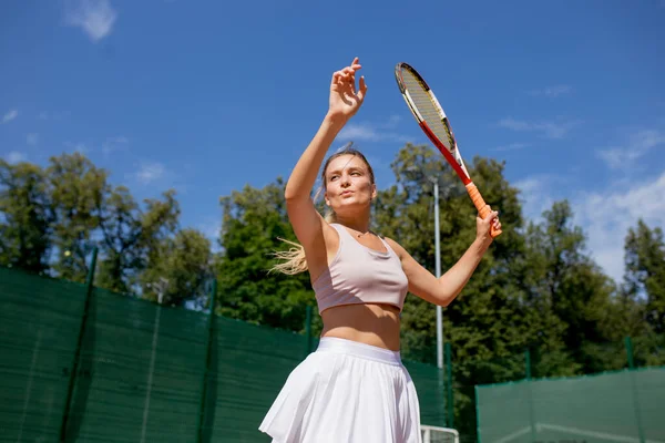 Sahada tenis oynamak için top servis eden bir kadın. — Stok fotoğraf