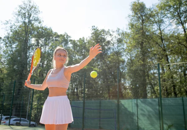 Mulher servindo a bola para um jogo de tênis no campo — Fotografia de Stock