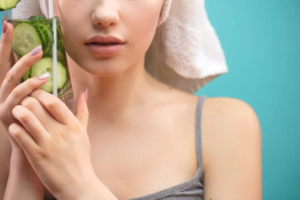 Mujer spa con toalla en la cabeza sosteniendo vaso de agua de pepino isoalted sobre azul —  Fotos de Stock