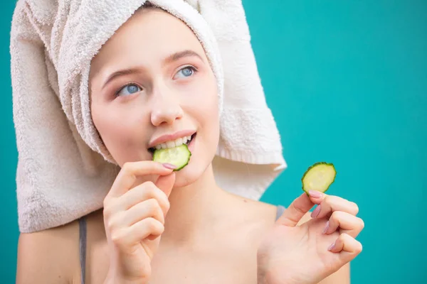 Mujer con una toalla en la cabeza divirtiéndose, cubriendo los ojos con rodajas de pepino. —  Fotos de Stock