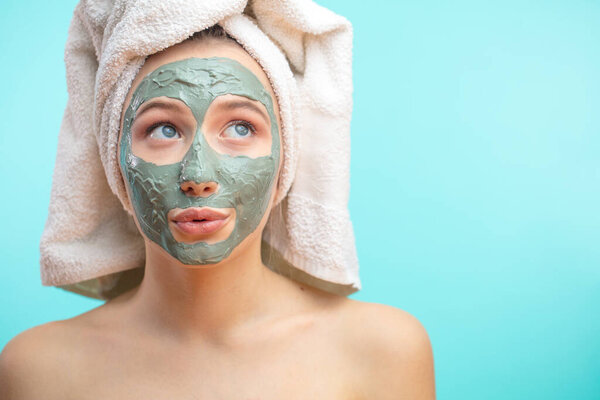 The girl in a mask for the face with a towel on his head