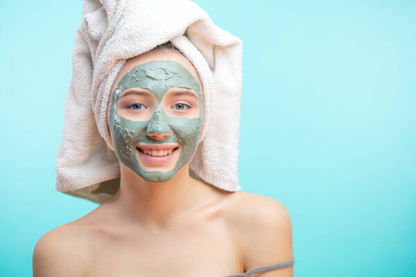 Woman with towel on head applying Facial clay Mask.