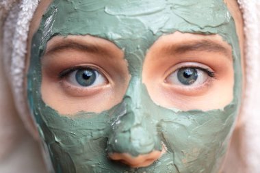 Yüzünde kil maske olan Makro kadın yüzü izole edilmiş, giyinmiş, makro