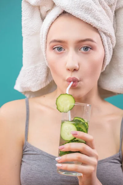 Mulher de spa com toalha na cabeça segurando vidro de água de pepino isoalted sobre azul — Fotografia de Stock