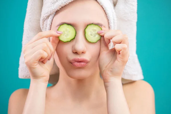 Mujer con una toalla en la cabeza divirtiéndose, cubriendo los ojos con rodajas de pepino. — Foto de Stock