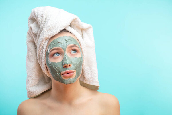 The girl in a mask for the face with a towel on his head