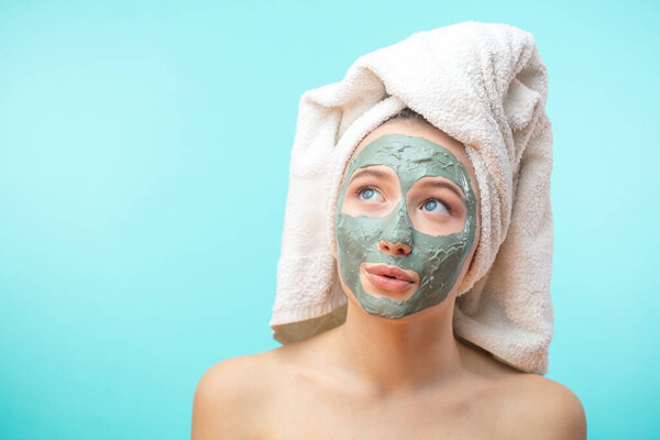 The girl in a mask for the face with a towel on his head