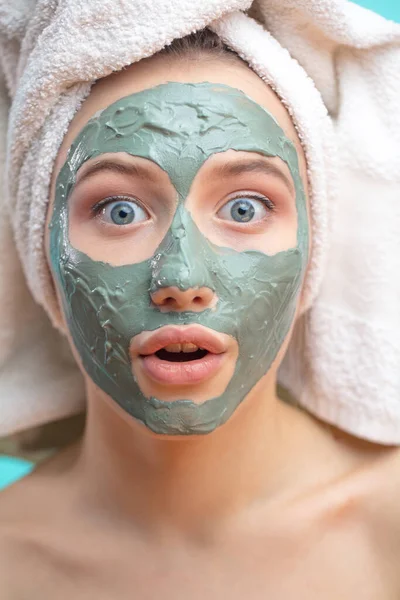 Macro shot of shoked surprised woman with clay facing mask and towel on face — Stock Photo, Image