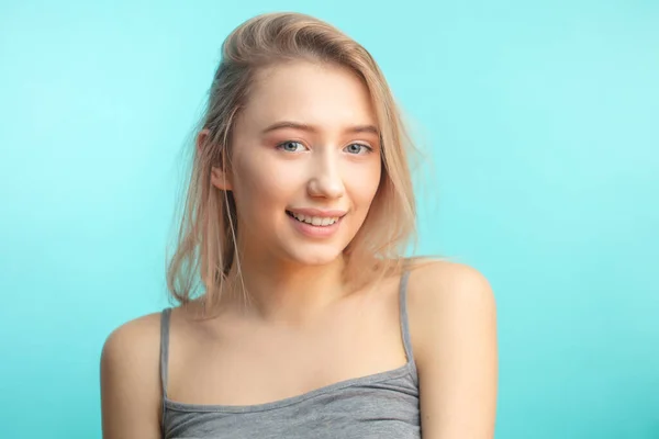 Szczęśliwa młoda kobieta ubrana we włosy jest zadowolona z pozytywnych wieści, patrząc w aparat z radosnym i czarującym uśmiechem. — Zdjęcie stockowe