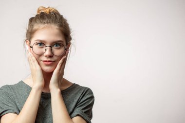 Şok olmuş kadın, böcek gözlü kameraya bakıyor, elleri yanaklarından tutuyor.