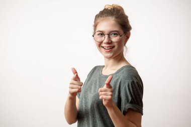 Genç bir kadın kamerayı işaret ederek işaret parmağıyla hareket ediyor..