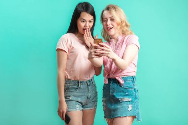 İki çok ırklı güzel Asyalı ve beyaz kadın stüdyoda selfie çekiyorlar.