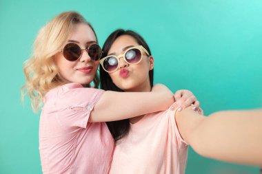 Farklı kızlar günlük kıyafetlerle çekim yapıyor. Mavi arka planda izole edilmiş selfie çekiyorlar..
