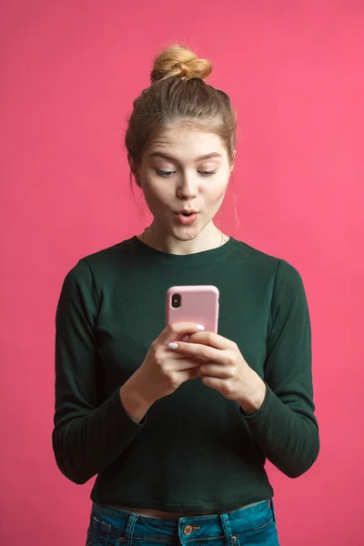 Портрет, если шокированная молодая девушка с мобильным телефоном изолированы на розовом фоне — стоковое фото