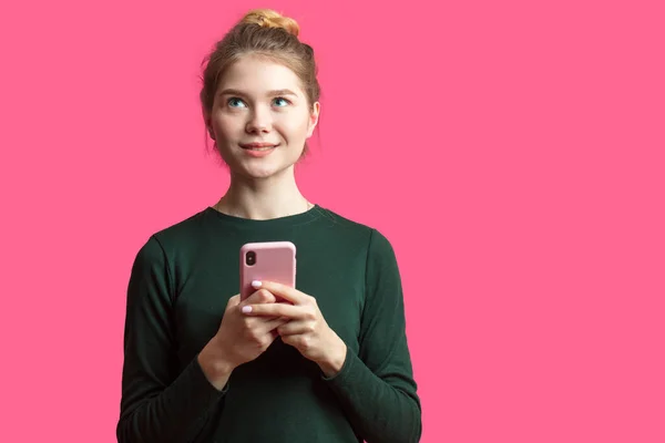 Retrato de una chica casual satisfecha sosteniendo teléfono móvil aislado sobre fondo rosa — Foto de Stock