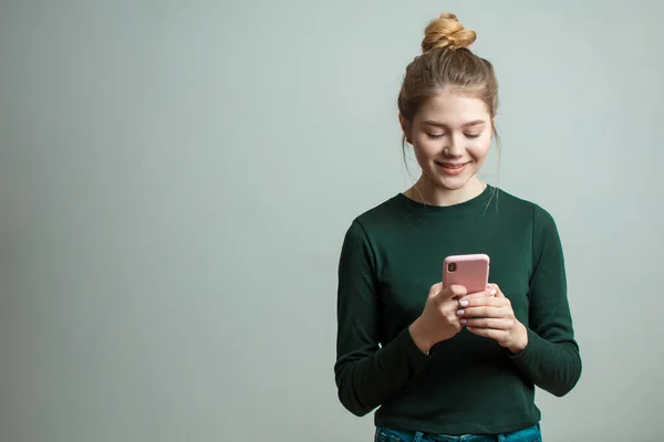 Mujer con camisa verde de manga larga usando un teléfono móvil aislado en un blanco — Foto de Stock