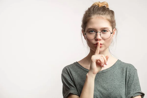 Mujer caucásica con moño de pelo manteniendo el dedo índice en los labios, aislado sobre blanco. — Foto de Stock