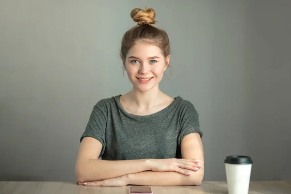 woman in casual clothes with her hair in bun looking at camera with smile