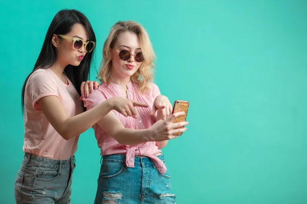 Dos multiétnicas hermosas mujeres asiáticas y caucásicas tomando selfie en estudio — Foto de Stock