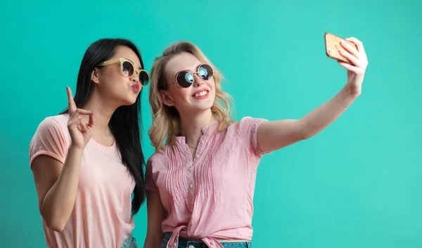 Felice diverse giovani ragazze prendendo selfie con smartphone contro muro blu — Foto Stock